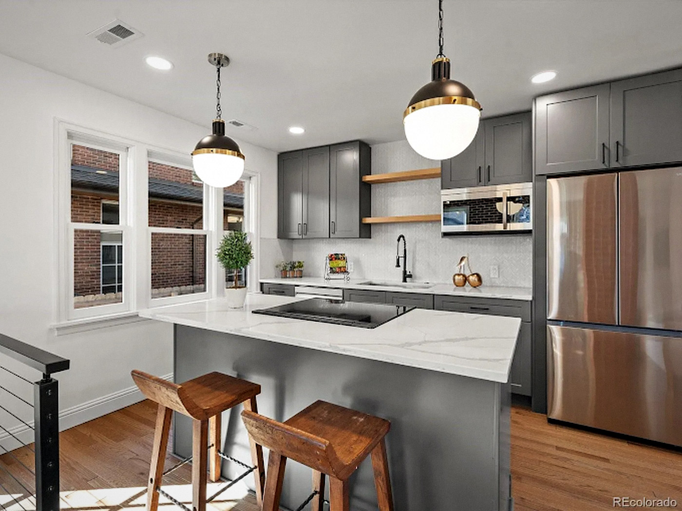 Modern kitchen with gray shaker cabinets, floating shelves, a quartz island and stainless appliances in Centennial, CO